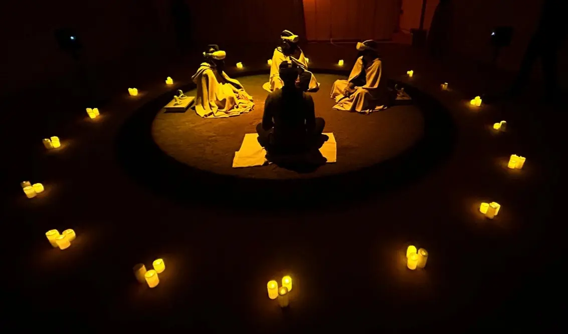 Les participants de l'expérience, assis par terre en cercle, avec leurs 
          oculus, illuminés seulement par des bougies