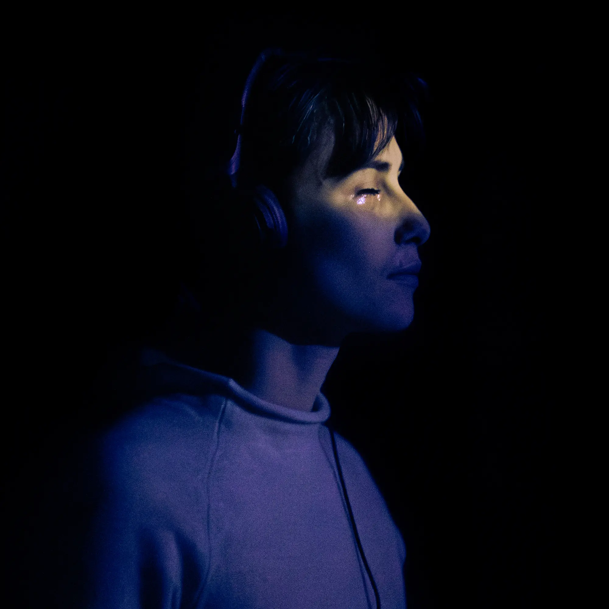 On devine les larmes d'une femme presque complètement cachée dans le noir